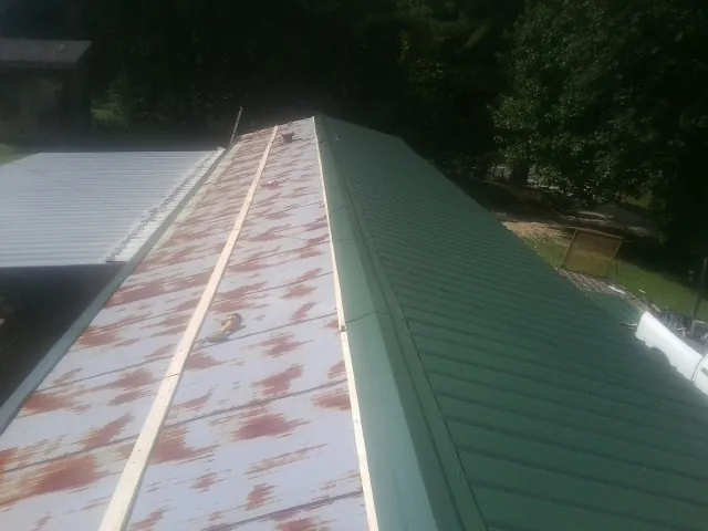 Old rusted panels beside newly installed green metal roofing — Wind Damage Roof Repair by Roofing Brothers in Trout Creek
