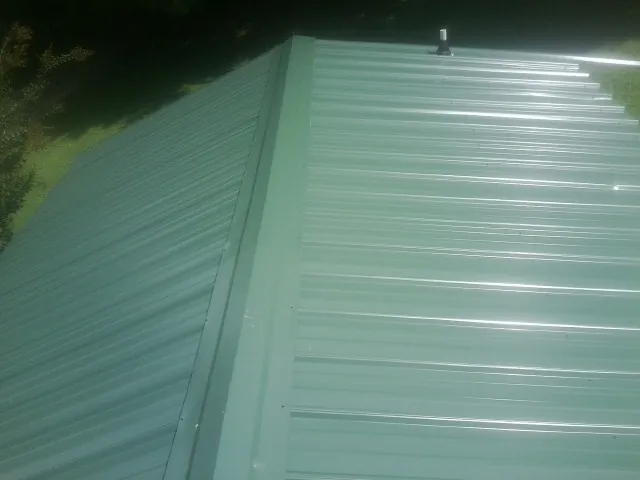 New green metal panels meeting at the ridge of a roof in Trout Creek