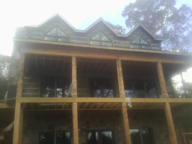 Dormers and porch framing on a large log home under construction — Roof Coating work by our crew in Trout Creek