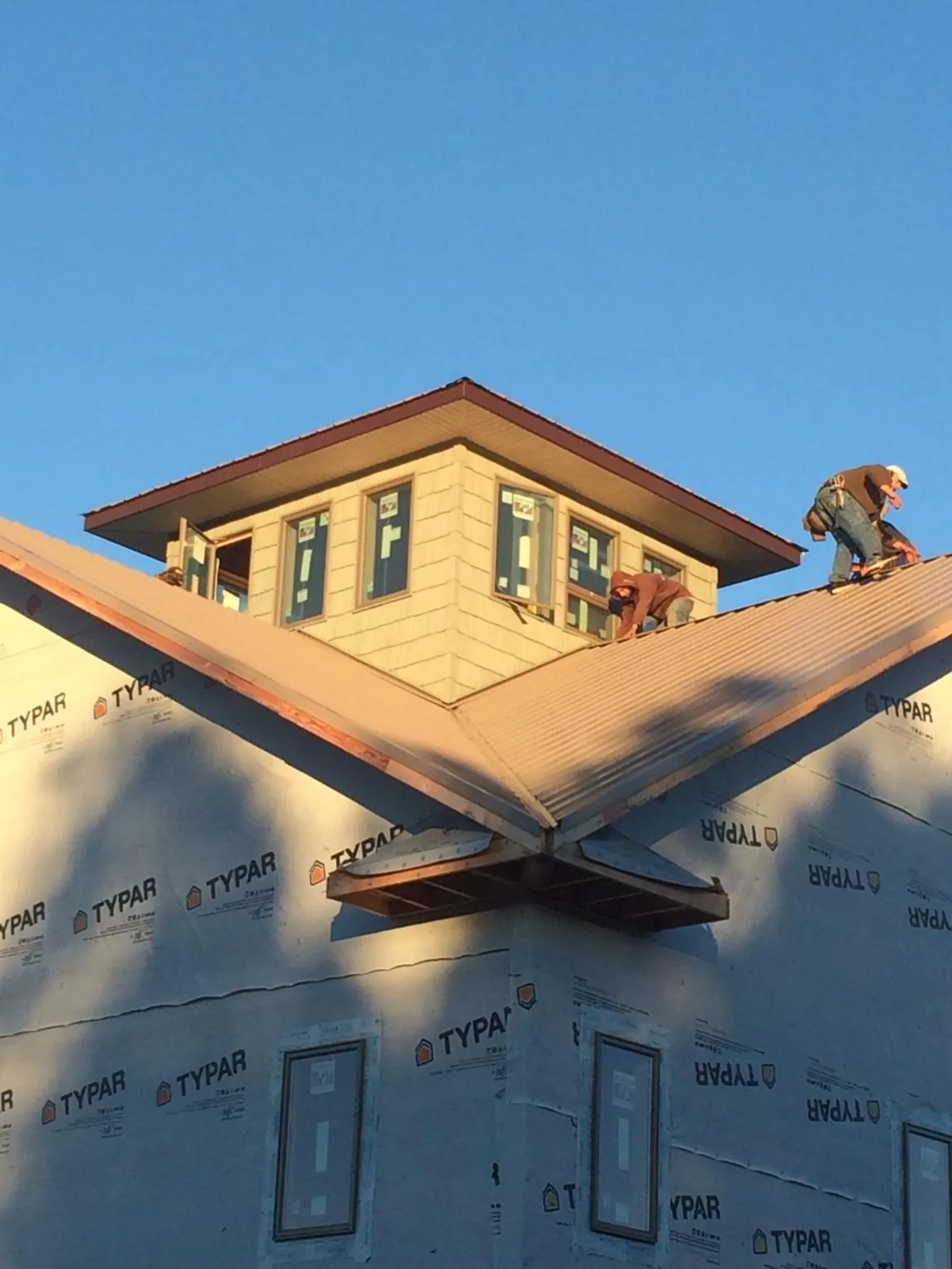 Roofers working around a rooftop cupola on a new metal roof at sunset — Roof Waterproofing in Trout Creek by Roofing Brothers